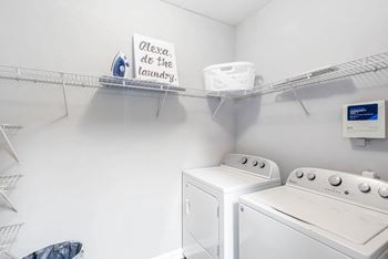 a washer and dryer in a white laundry room with a shelf above them